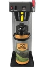 Commercial coffee brewing machine with a large coffee dispenser labeled "CAFFEIN8" and a contact phone number on the dispenser.