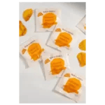 Several single-serve nacho cheese sauce packets and some spilled cheese are scattered on a white surface.